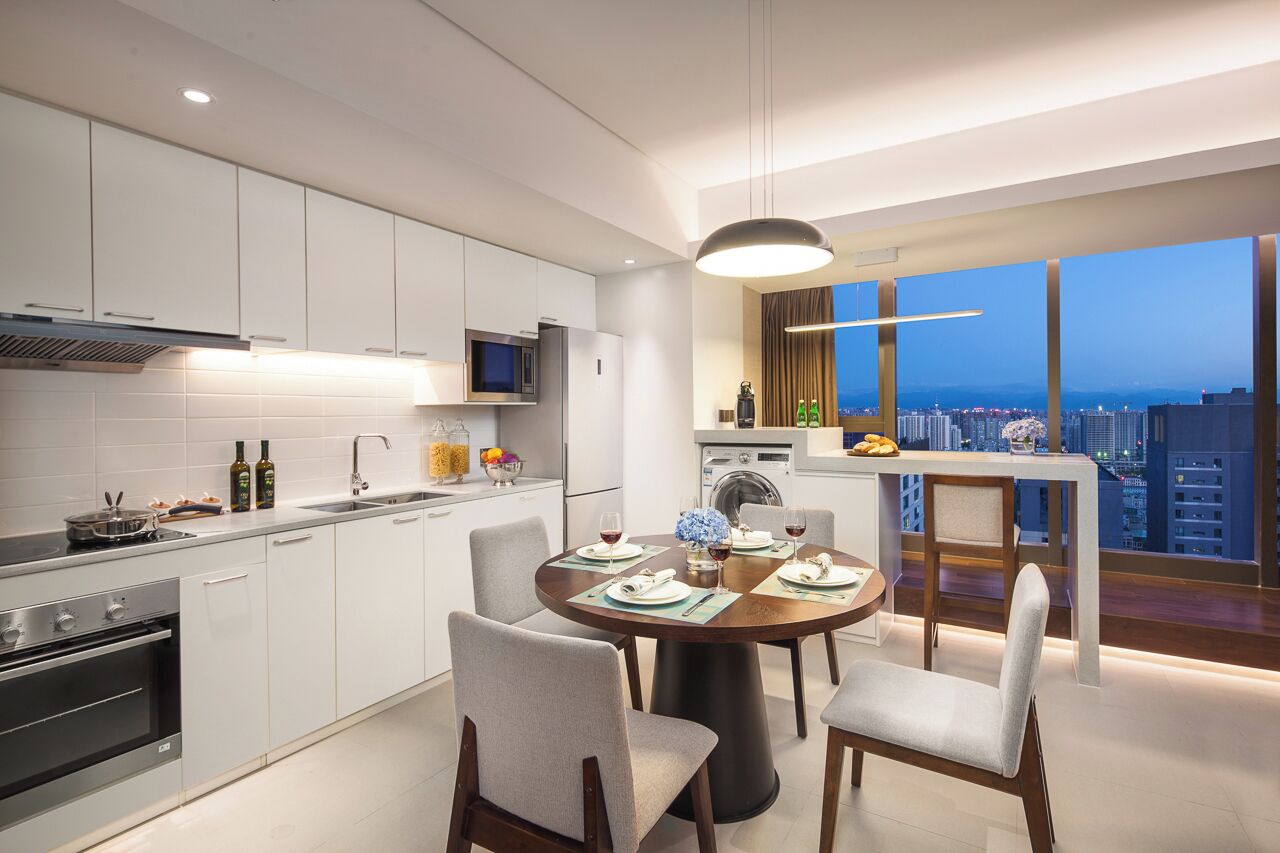 A modern kitchen with a dining area, a large window with a city view, and a dining table set for four.