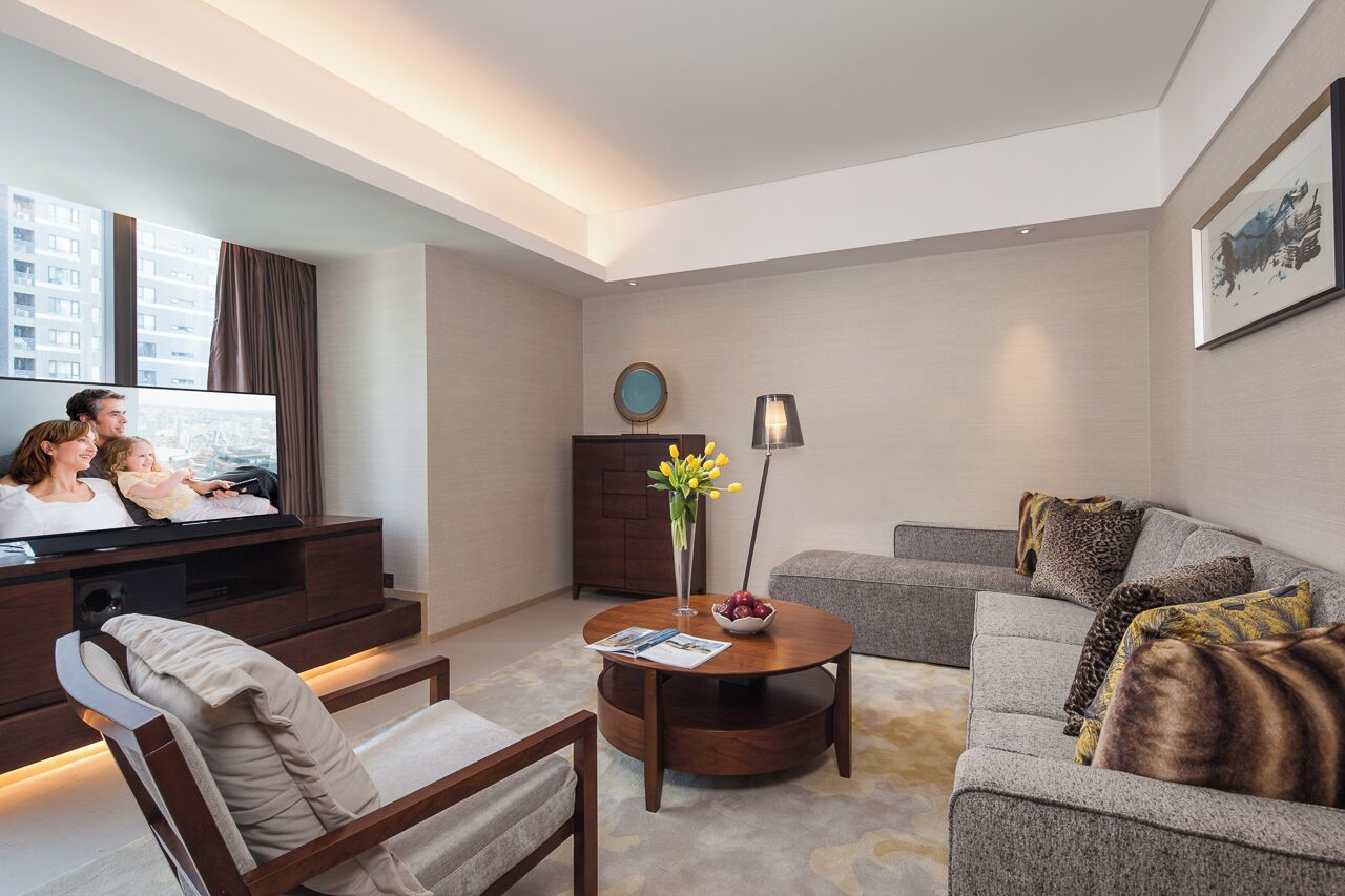A modern living room with a sofa, armchair, coffee table, TV, and a cabinet.