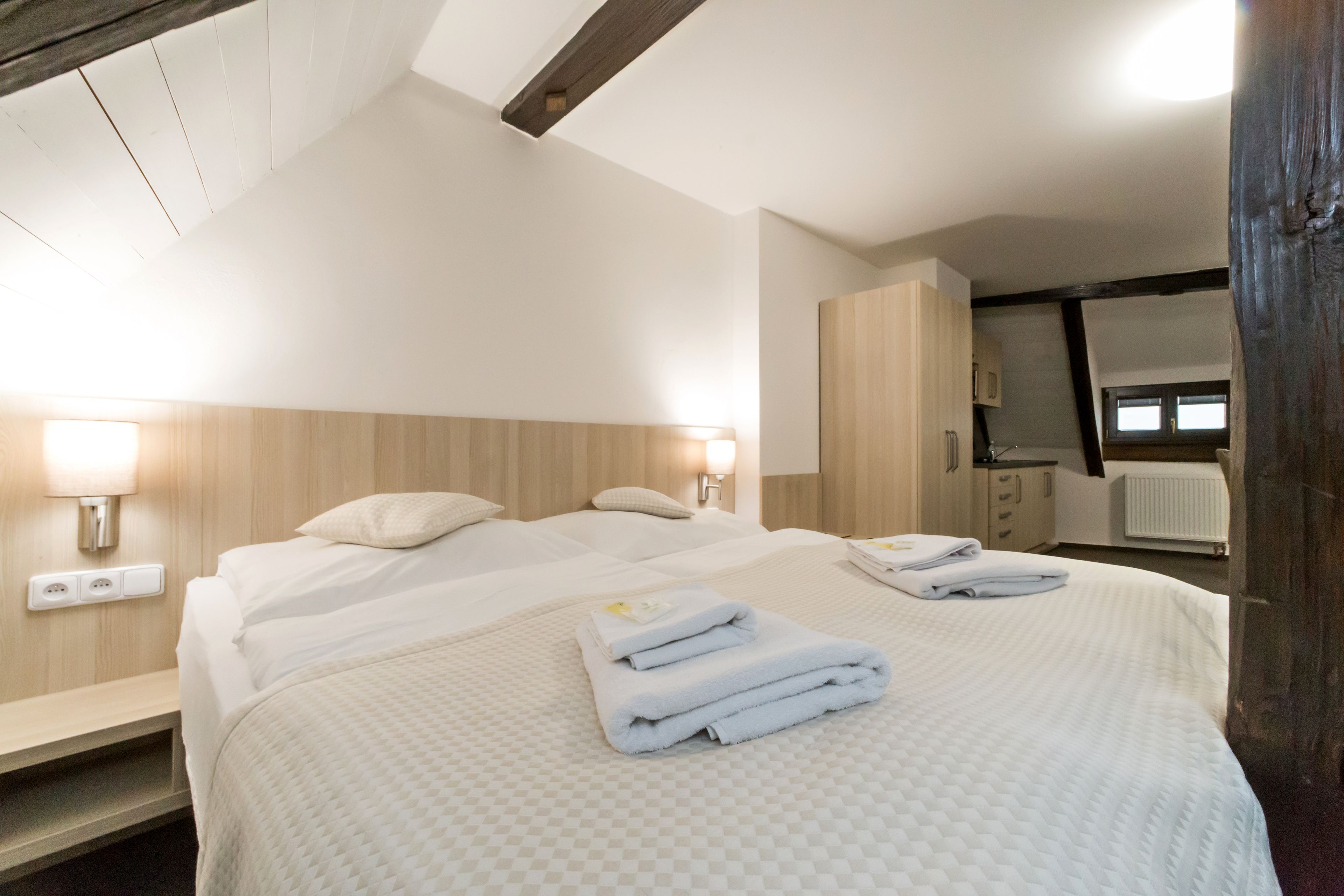 Une chambre d’hôtel avec un grand lit, deux tables de chevet, une armoire et un miroir.
