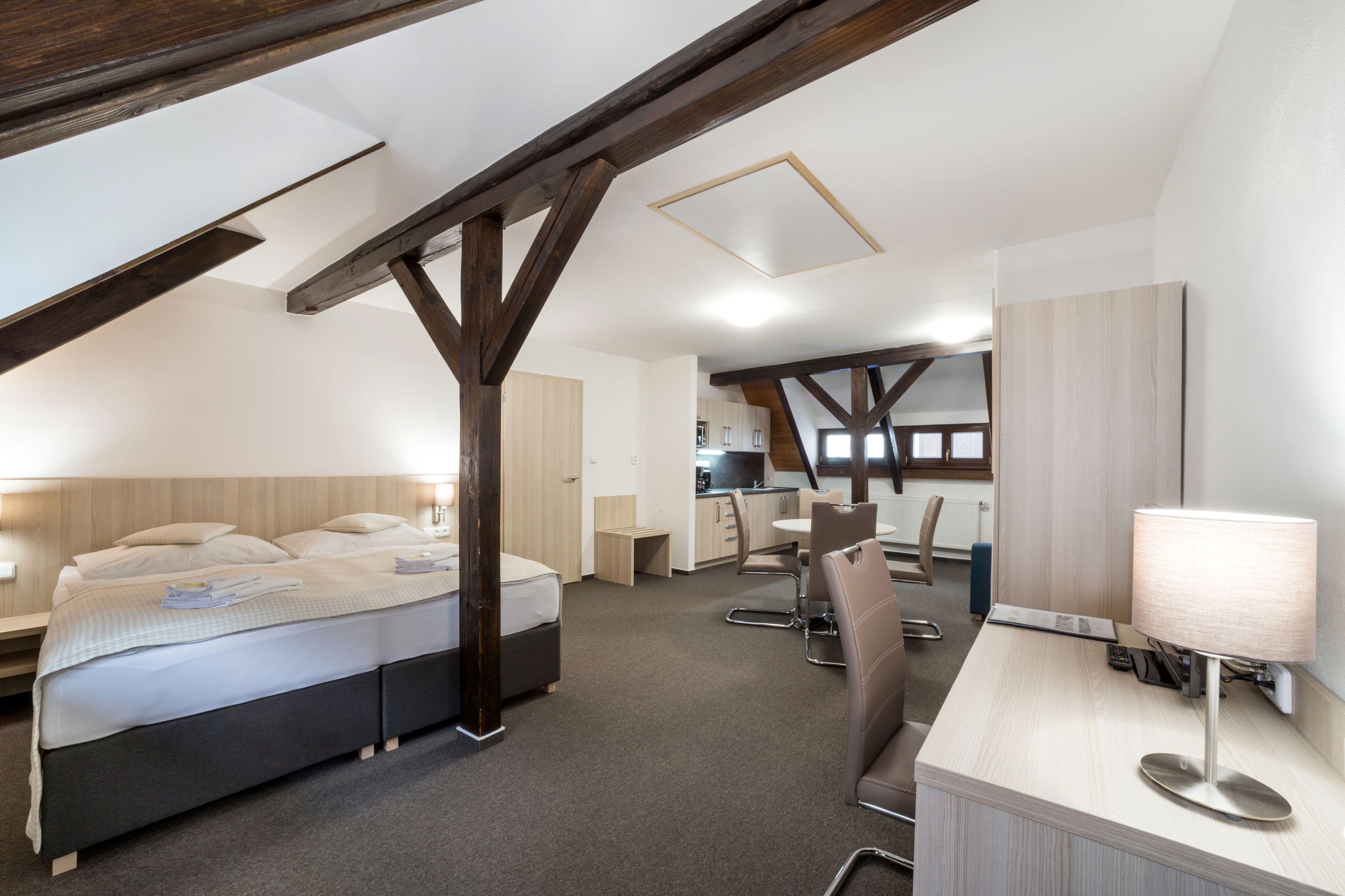 Habitación de hotel moderna con techo estilo loft, cama, escritorio y silla.