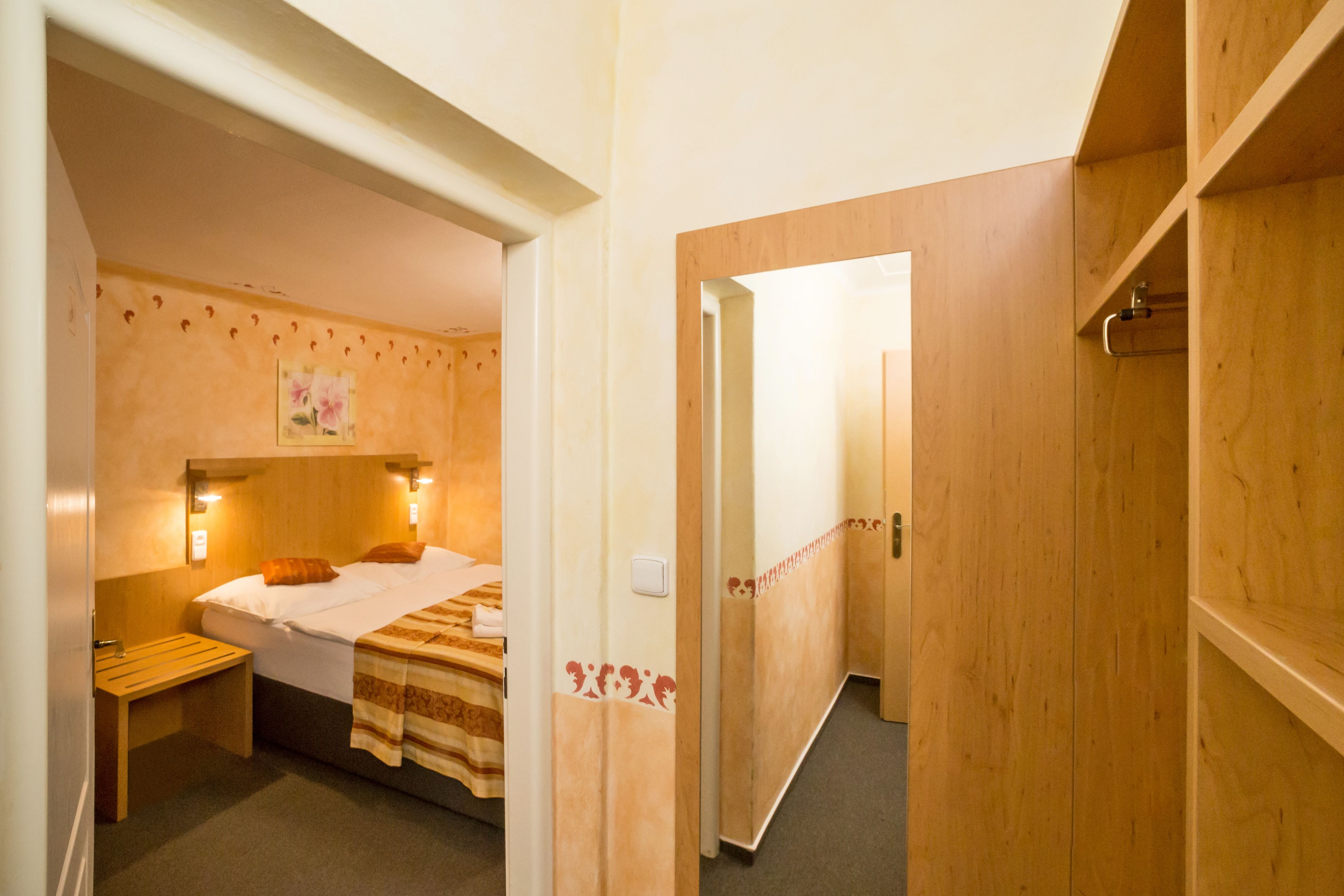 Une chambre d’hôtel avec un lit, une table de chevet et une armoire en bois.