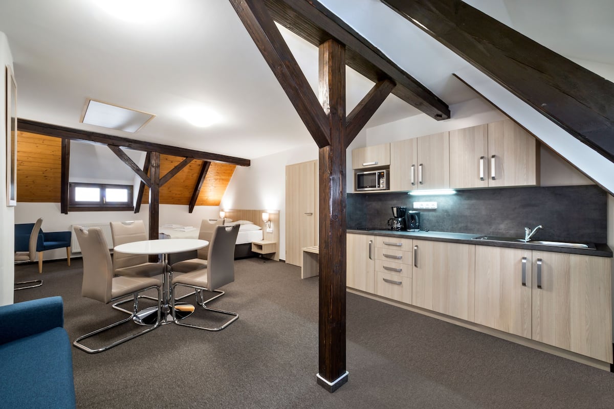 Una habitación moderna estilo loft con comedor, cocina y techo inclinado.