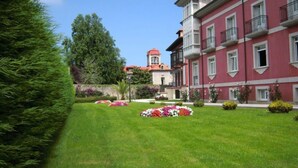 Un bâtiment à la façade rouge et doté de nombreuses fenêtres, entouré de pelouses bien entretenues et de parterres de fleurs.