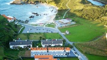 Vista aérea de una zona costera con un estacionamiento, edificios y una playa.