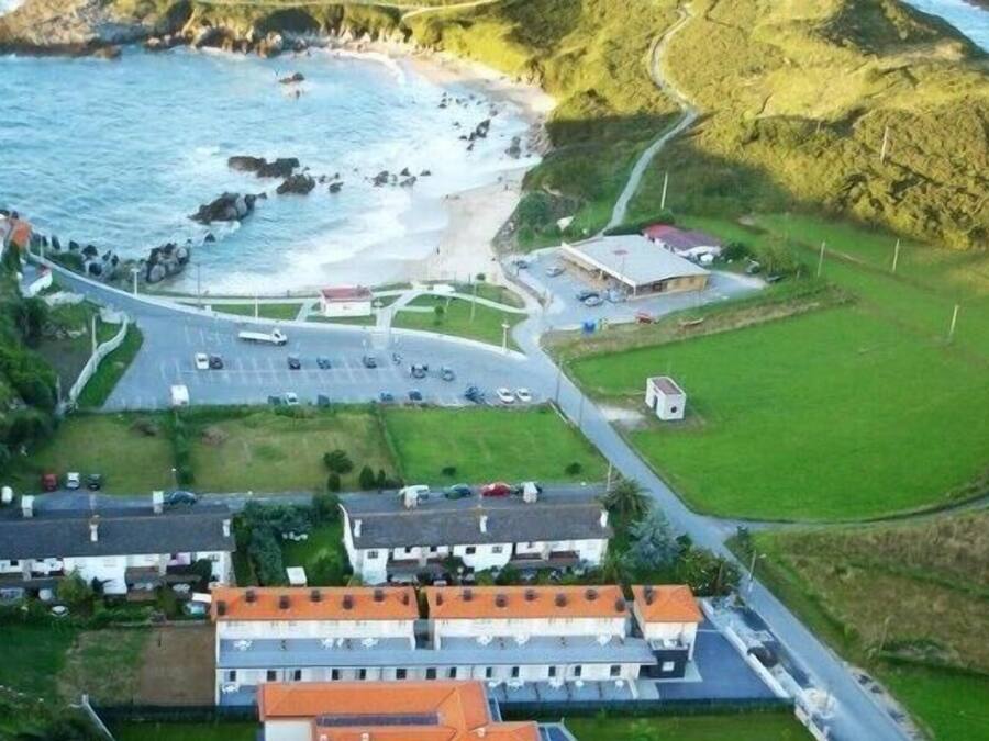 Vista aérea de una zona costera con un estacionamiento, edificios y una playa.