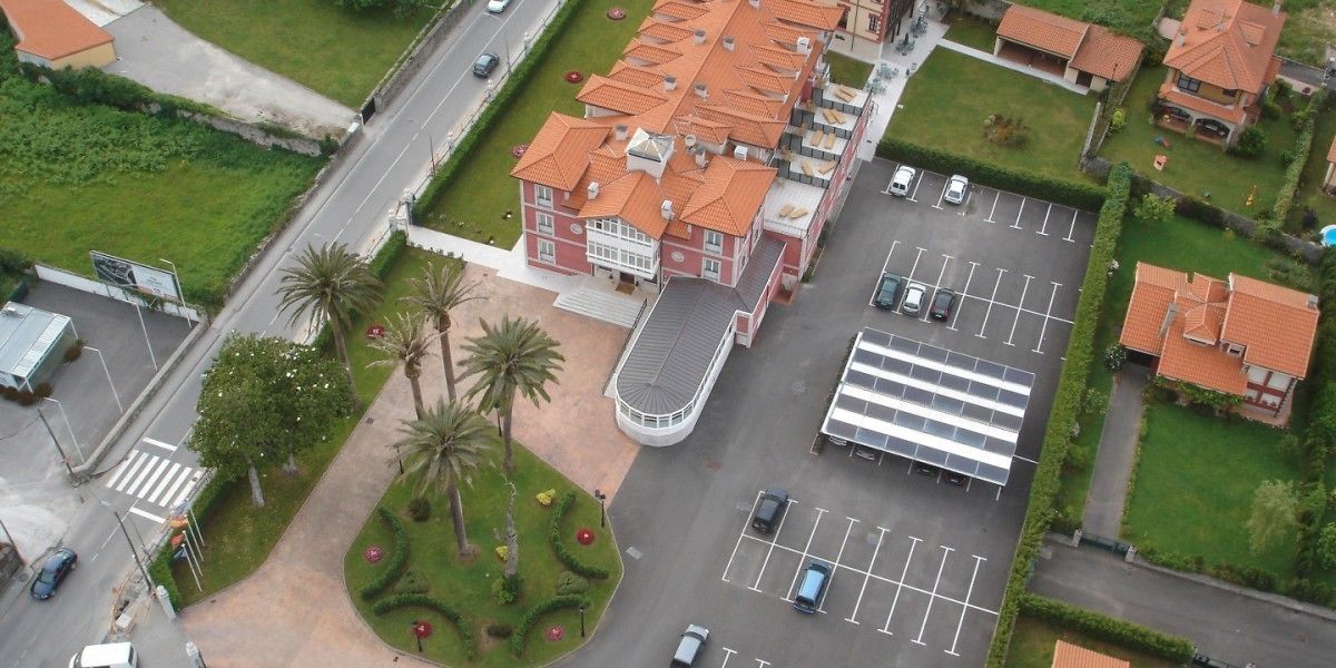 Vue aérienne d’un bâtiment avec un parking, une allée sinueuse et un espace paysager agrémenté de palmiers.