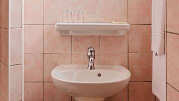 Un baño con lavamanos blanco, un espejo y un estante sobre el lavamanos.