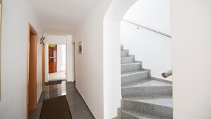 A hallway with a wooden door, a framed picture on the wall, and a staircase with stone steps. - Hotel Schwan (Eschweiler)