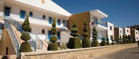 A white building with blue railings and a stone wall.