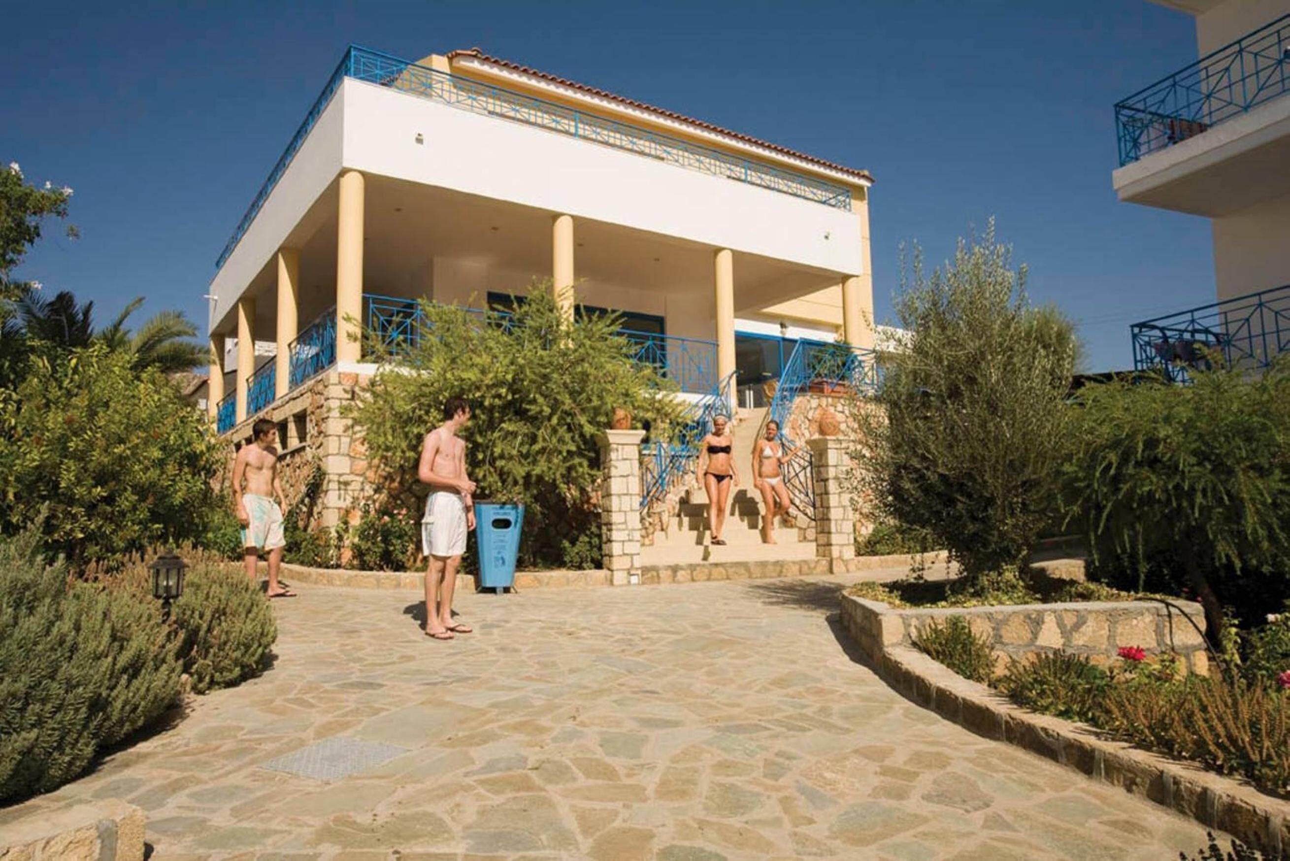 A building with a covered outdoor area, stone steps, and a blue railing.