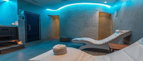 A spa room with a stone wall, a massage table, and a wooden bench.