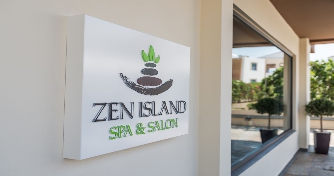 Une enseigne pour le «Zen Island Spa & Salon », avec un logo représentant une main tenant une pierre et une plante.