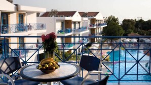 Un balcon avec une table, des chaises et une vue sur une piscine.