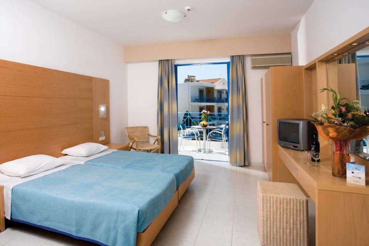 Une chambre d’hôtel avec un lit, un bureau avec une télévision, une chaise et un balcon avec vue.