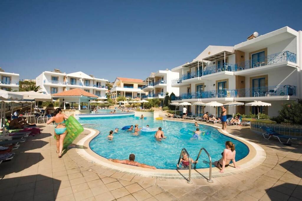 A swimming pool area with multiple levels of balconies, sun loungers, and umbrellas.
