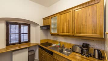 A kitchen with wooden cabinets, a stainless steel sink, a coffee maker, and a window with a view.