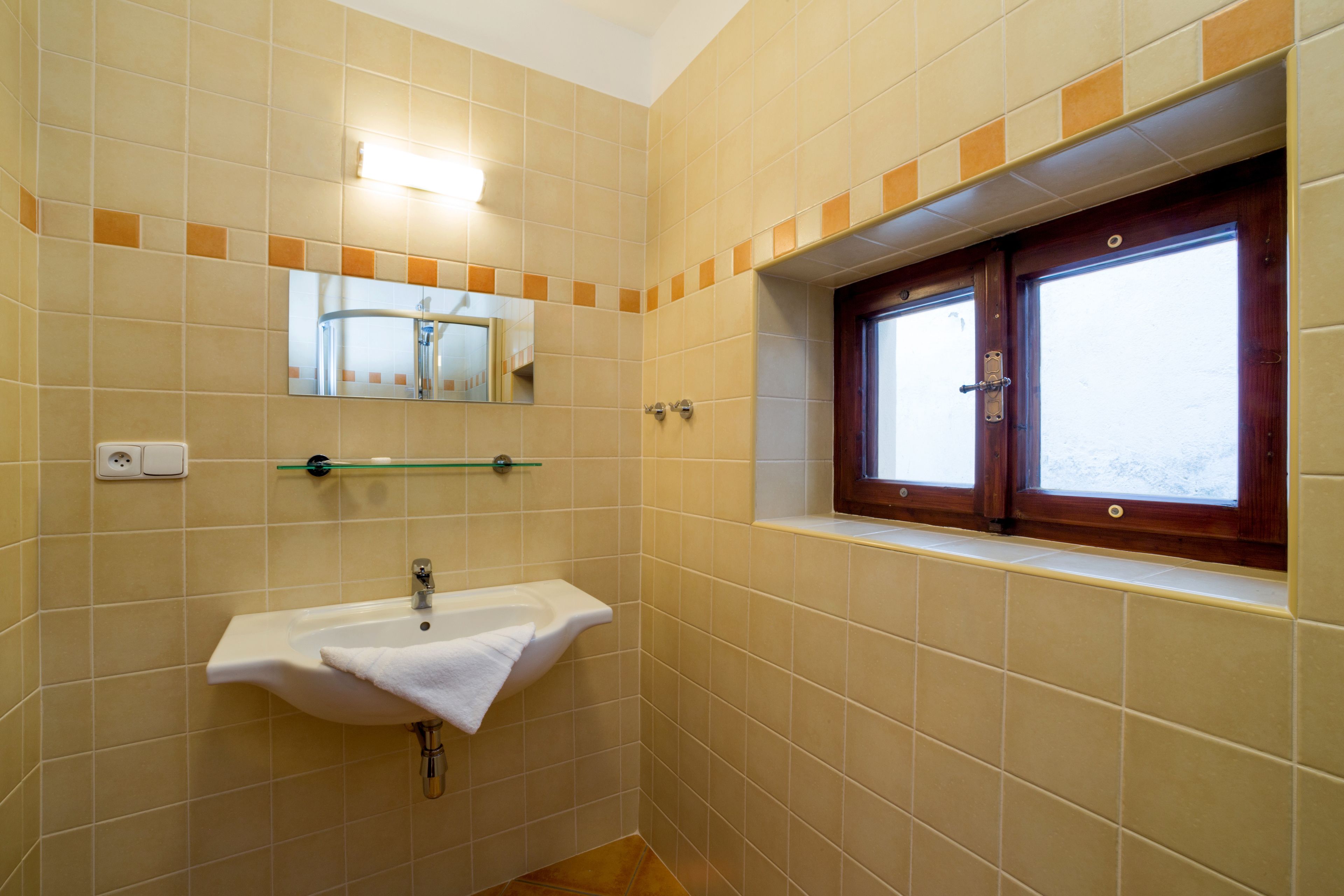 Un bagno con lavandino, specchio e finestra.