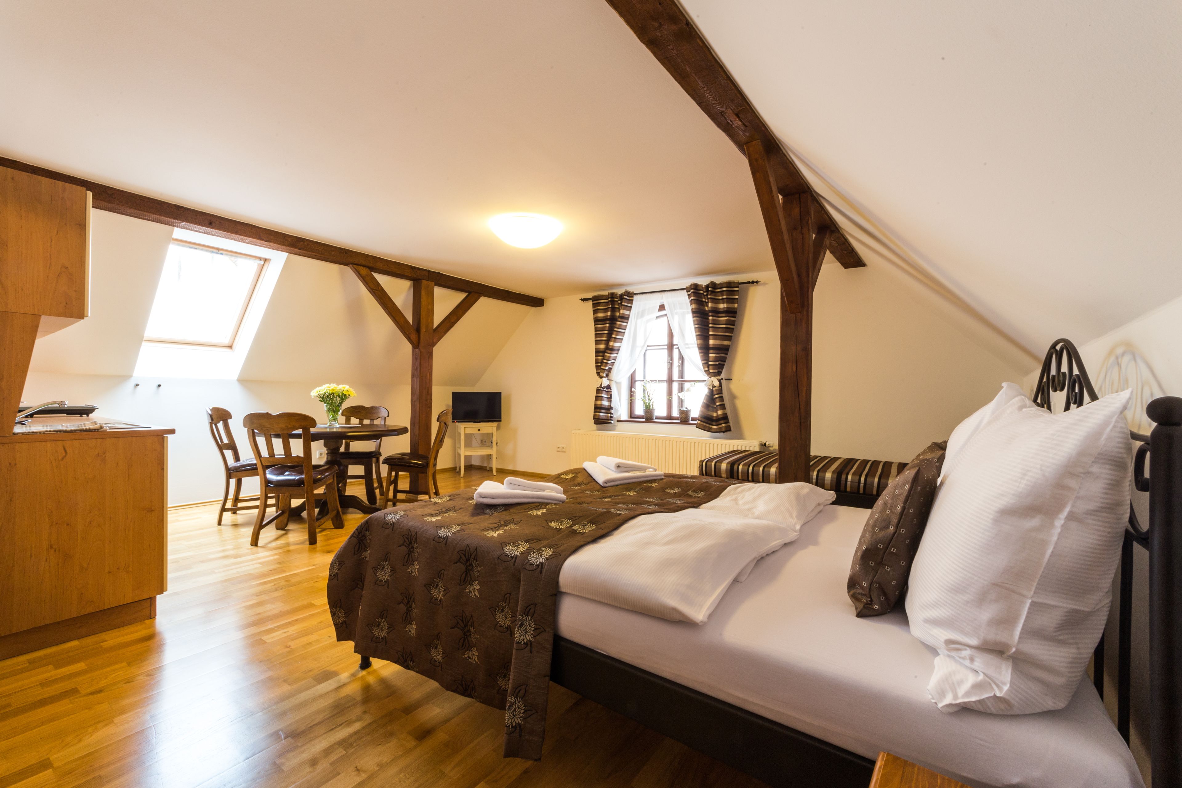 A bedroom with a bed, wooden furniture, a desk, and a window.