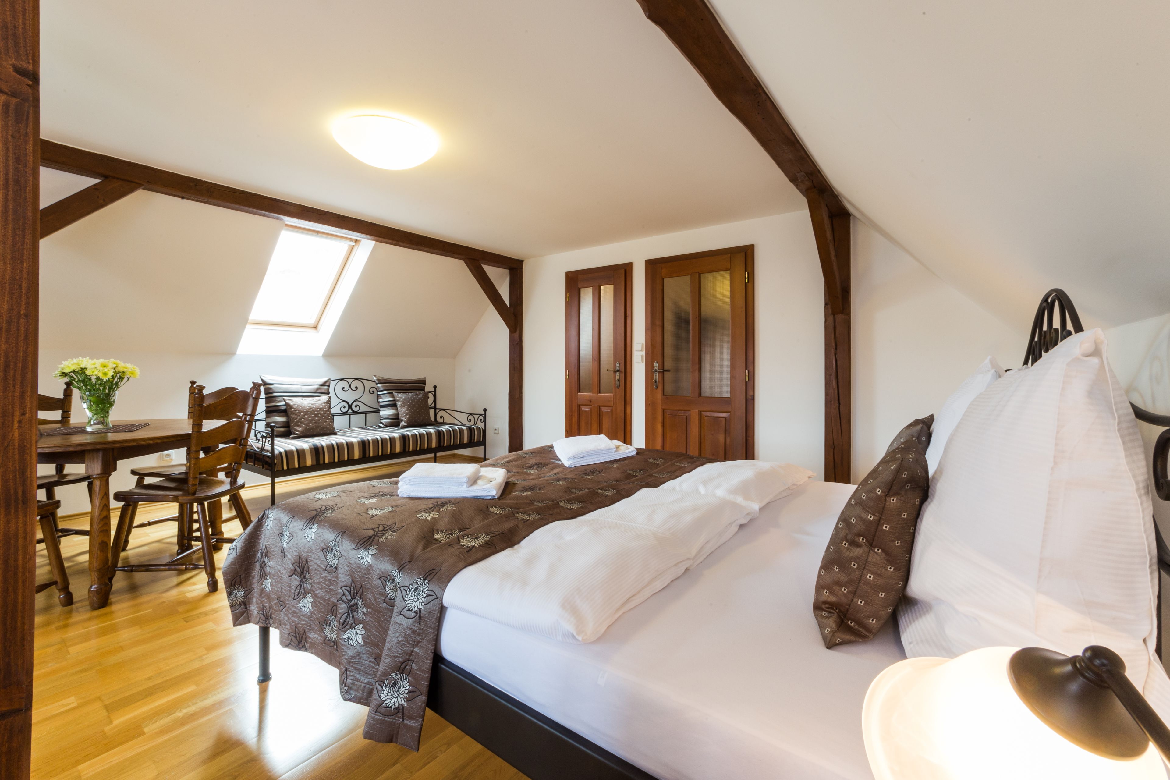 A bedroom with a bed, a desk, and a chair. There is a skylight above the desk.