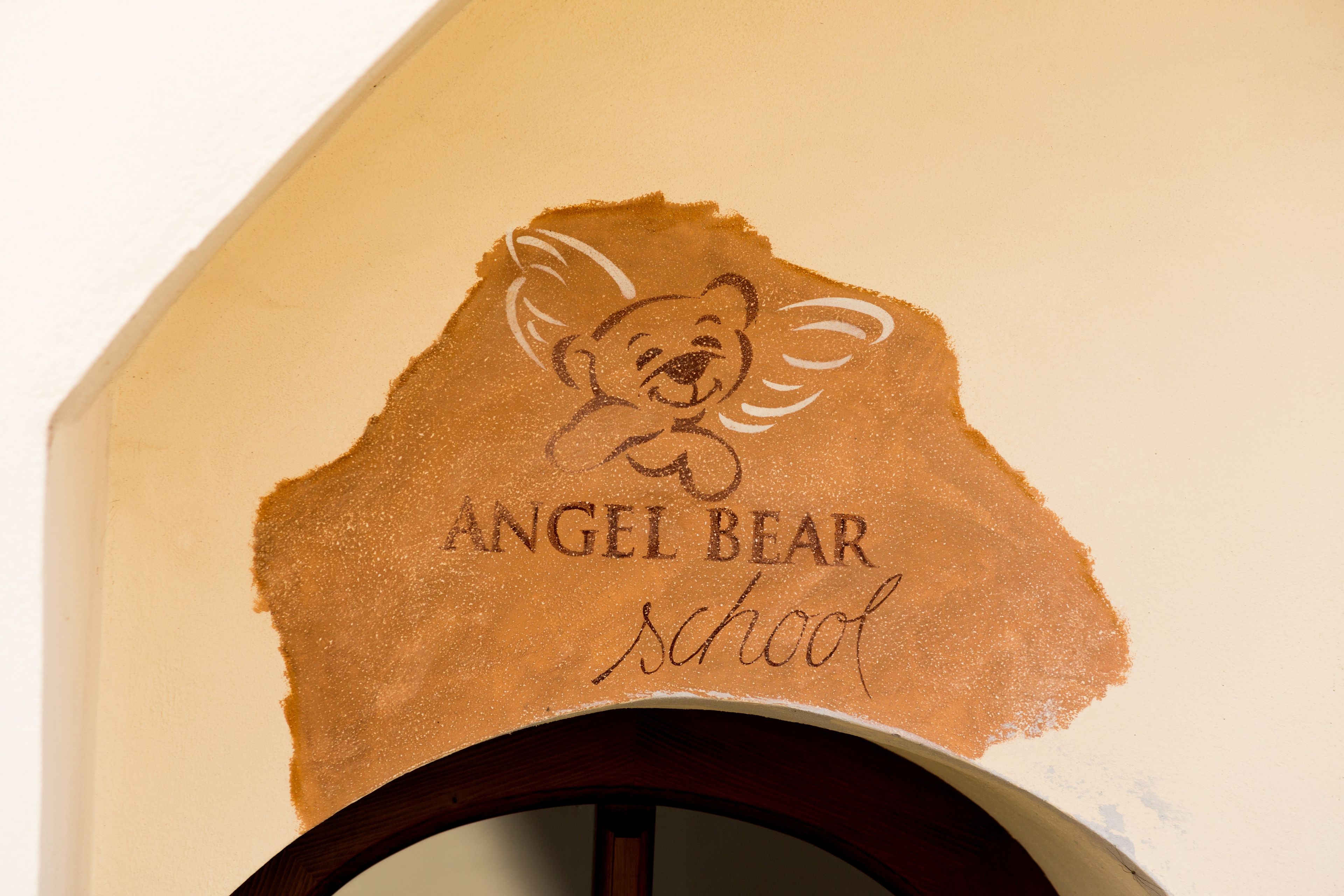 Un mur orné d’un logo représentant un ours et sur lequel est gravé le texte « Angel Bear School ».