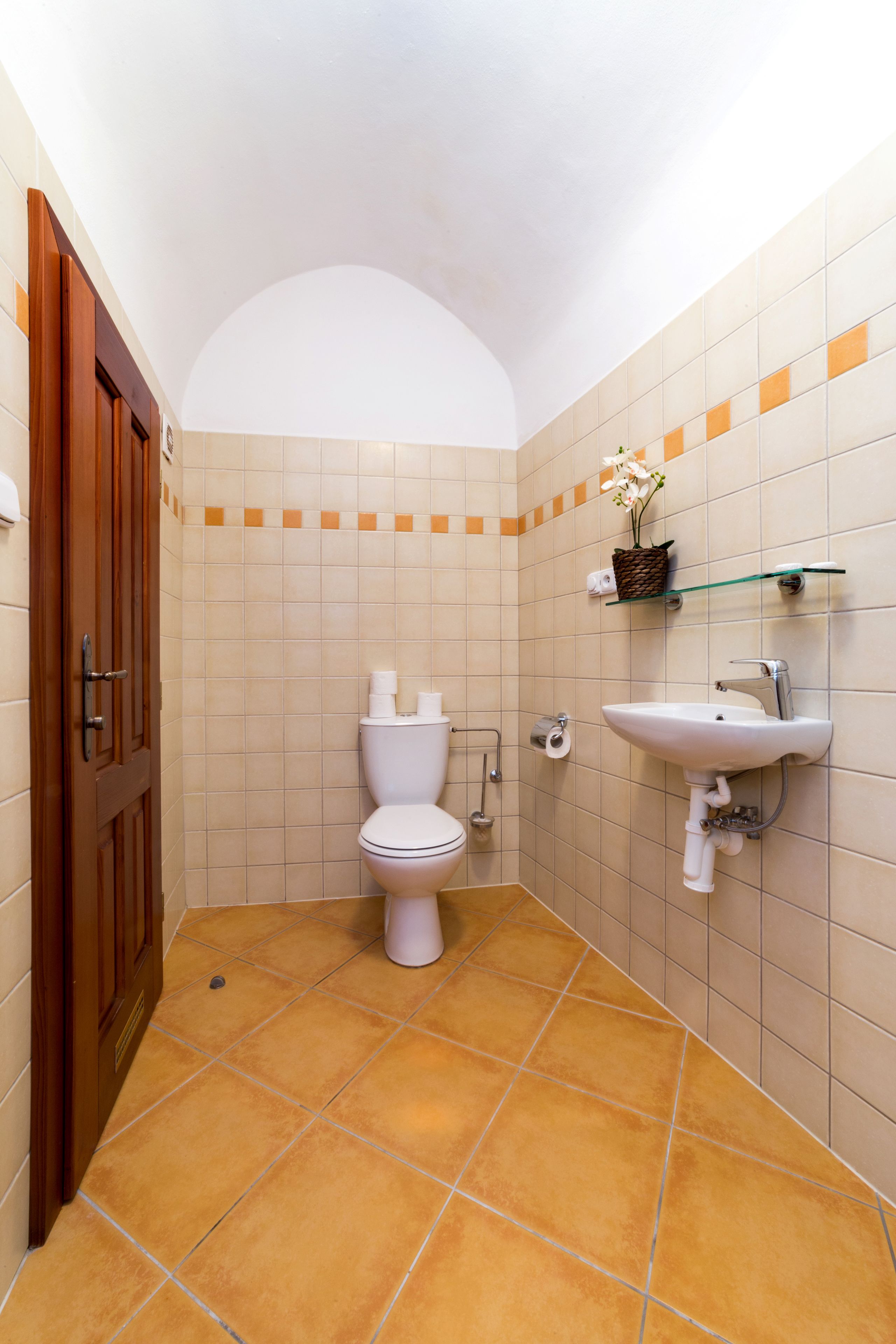 A bathroom with a toilet, sink, and tiled walls.