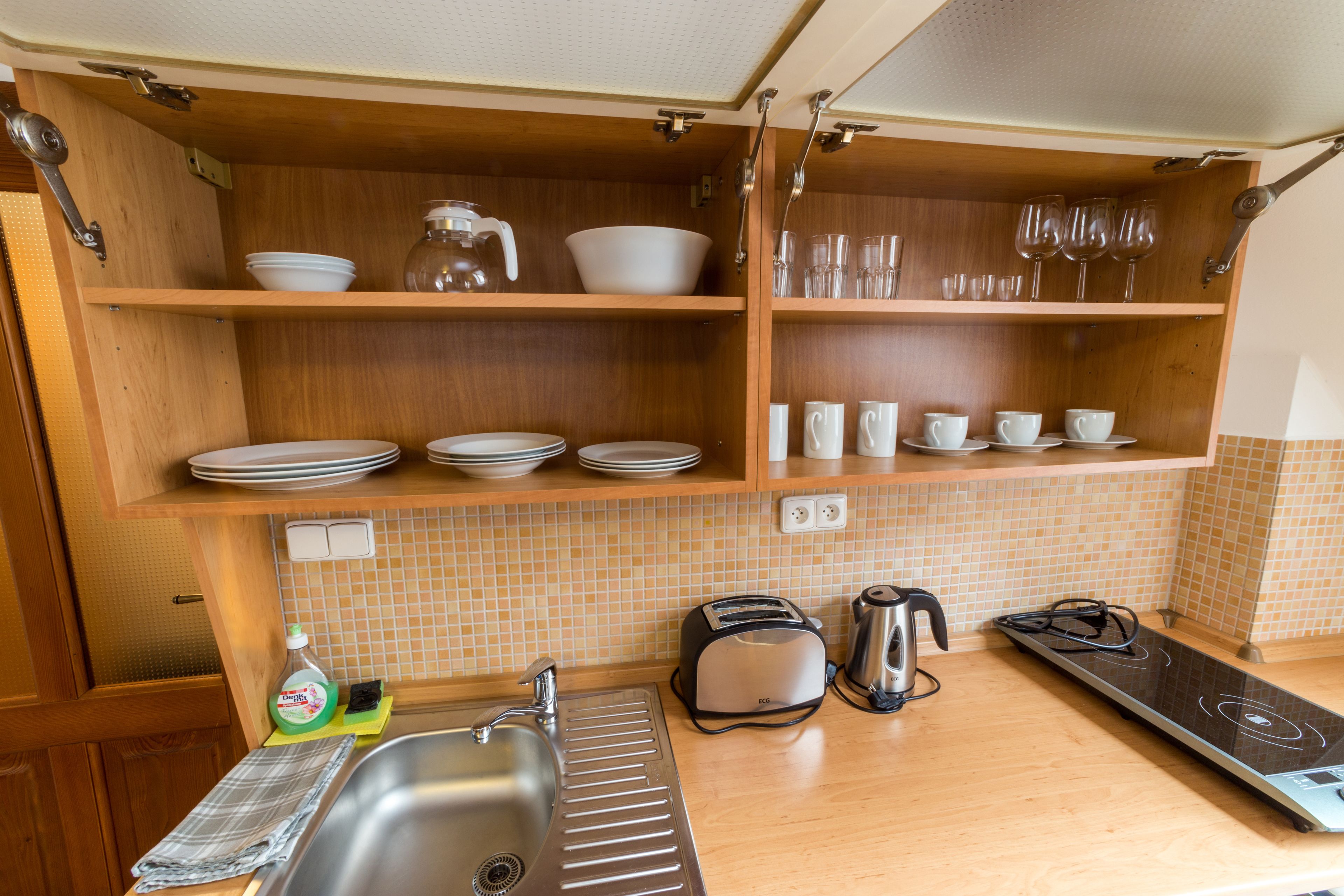 Een compacte keuken met houten planken, een spoelbak, een broodrooster, een waterkoker en een fornuis.