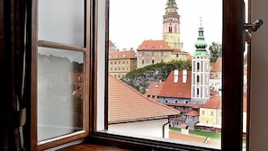 Una habitación con ventana que da a un edificio histórico con una torre.