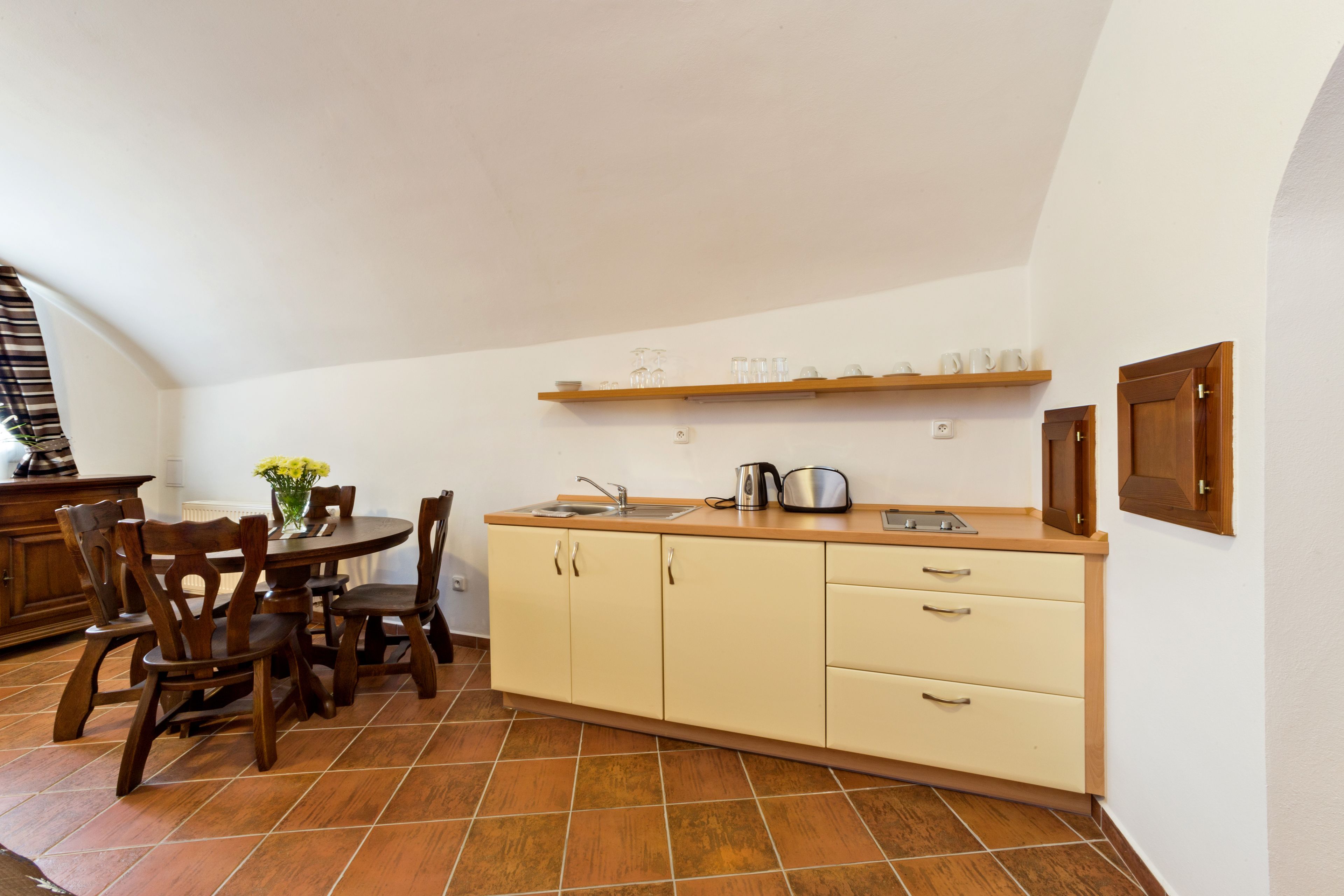 Cozinha compacta com mesa, cadeiras, pia e fogão.