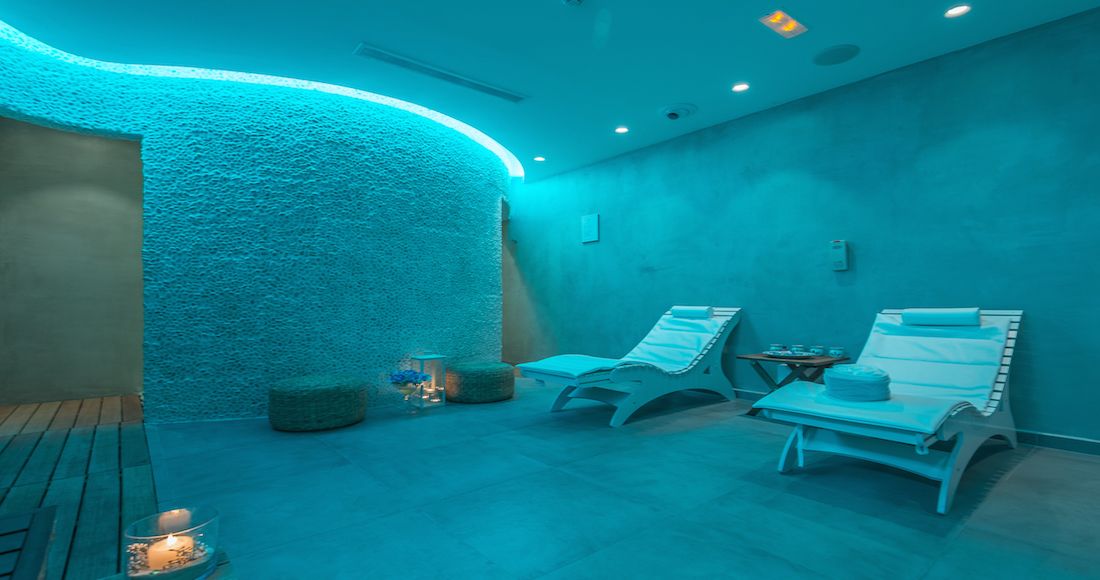 Une salle de spa équipée de deux chaises longues, d’un mur à texture et d’un plancher en bois.
