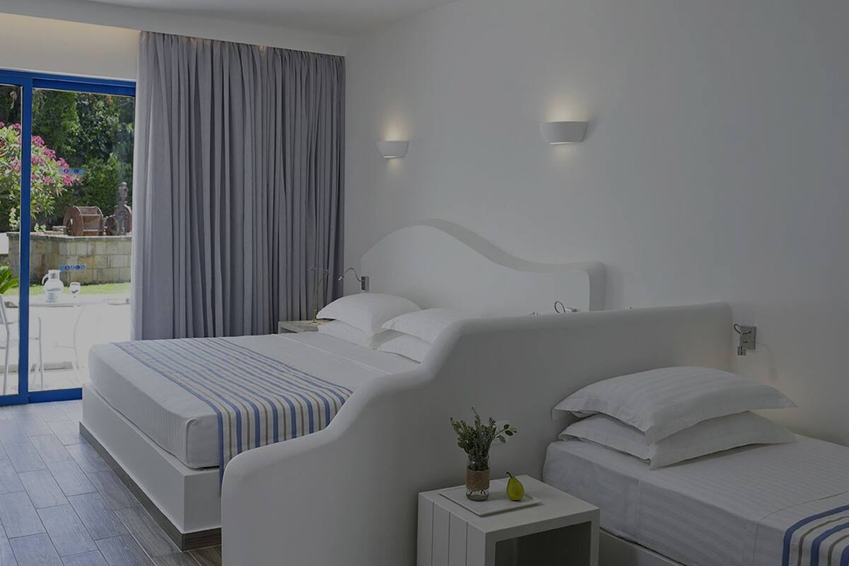 A modern hotel room with a large bed, a smaller bed, a nightstand, and a view of the outdoors.