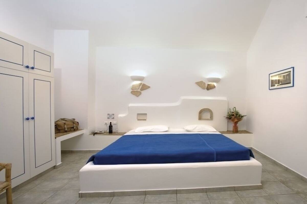 A bedroom with a bed, bedside tables, a wardrobe, and a wall-mounted light fixture.