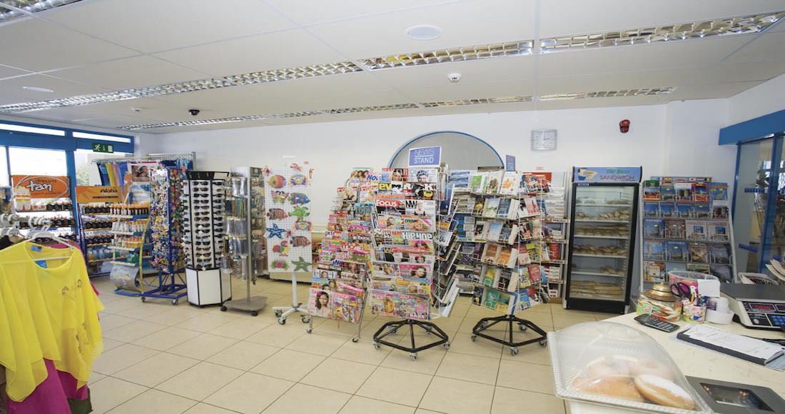 A bookstore with multiple magazine racks and a refrigerated display case.