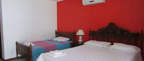 A hotel room with two beds, a red wall, and an air conditioning unit.