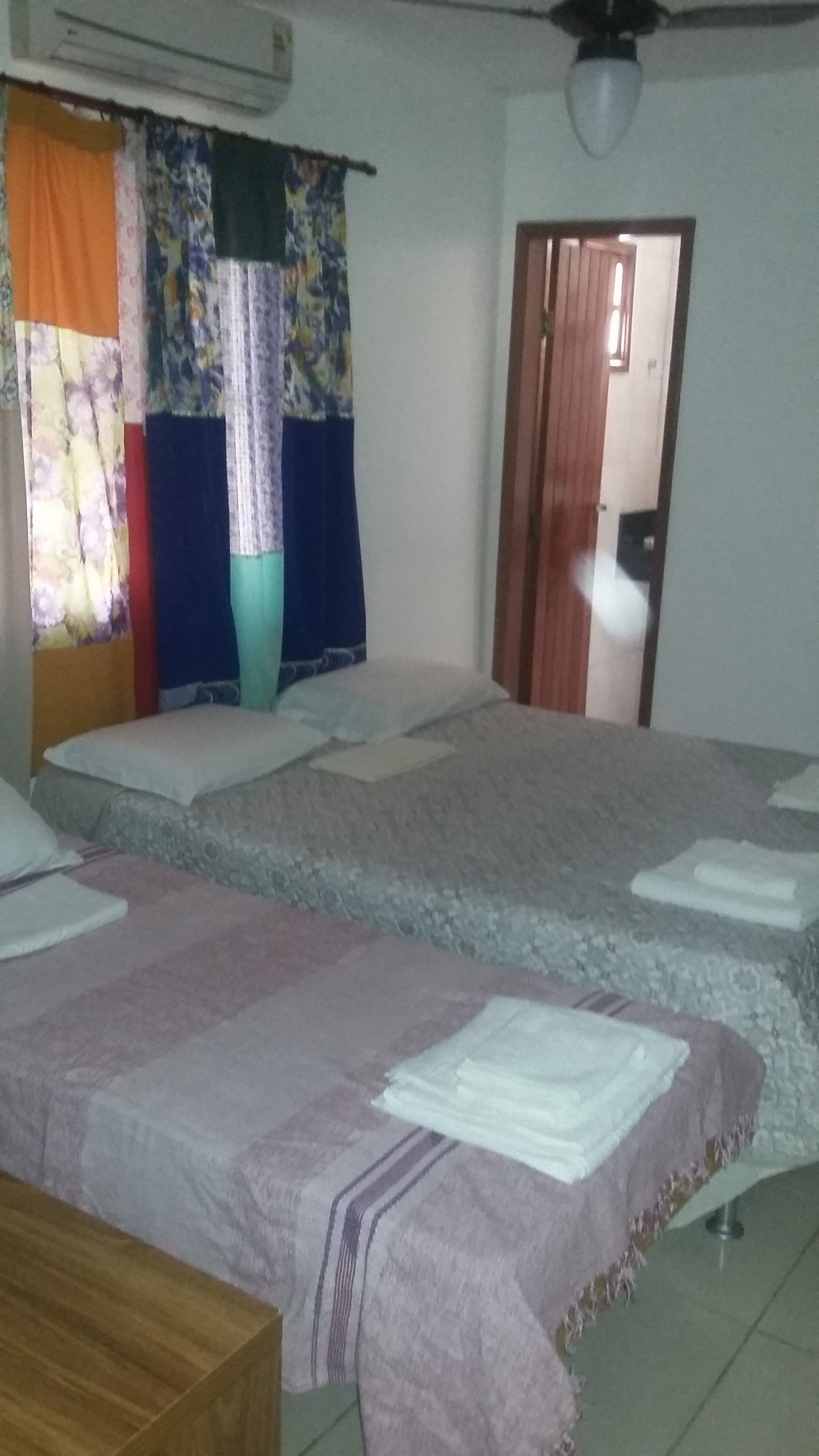 A bedroom with two beds, a wooden dresser, and a door leading to another room.