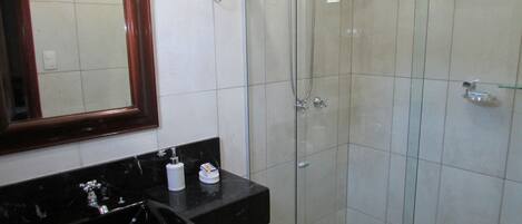 A bathroom with a glass-enclosed shower, a black countertop, and a mirror.