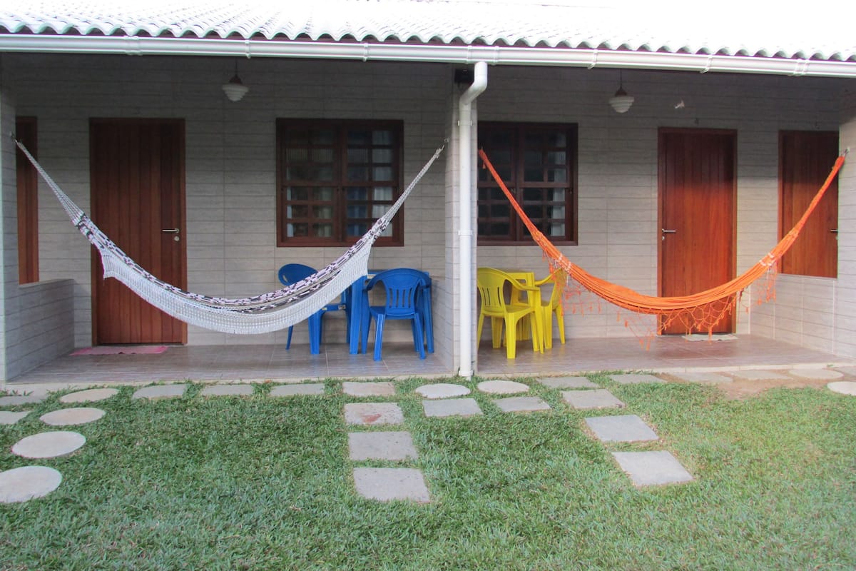 Una casa con un porche cubierto, dos hamacas y mobiliario exterior.