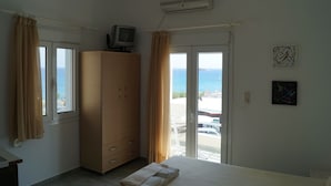 A bedroom with a bed, a wardrobe, a television, and a view of the sea through a sliding door. - Agia Fotia (Ierapetra)