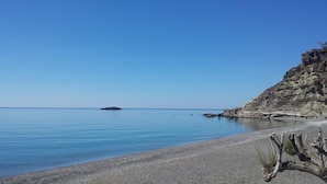 A beach with calm waters, a rocky cliff, and sparse vegetation. - Agia Fotia (Ierapetra)