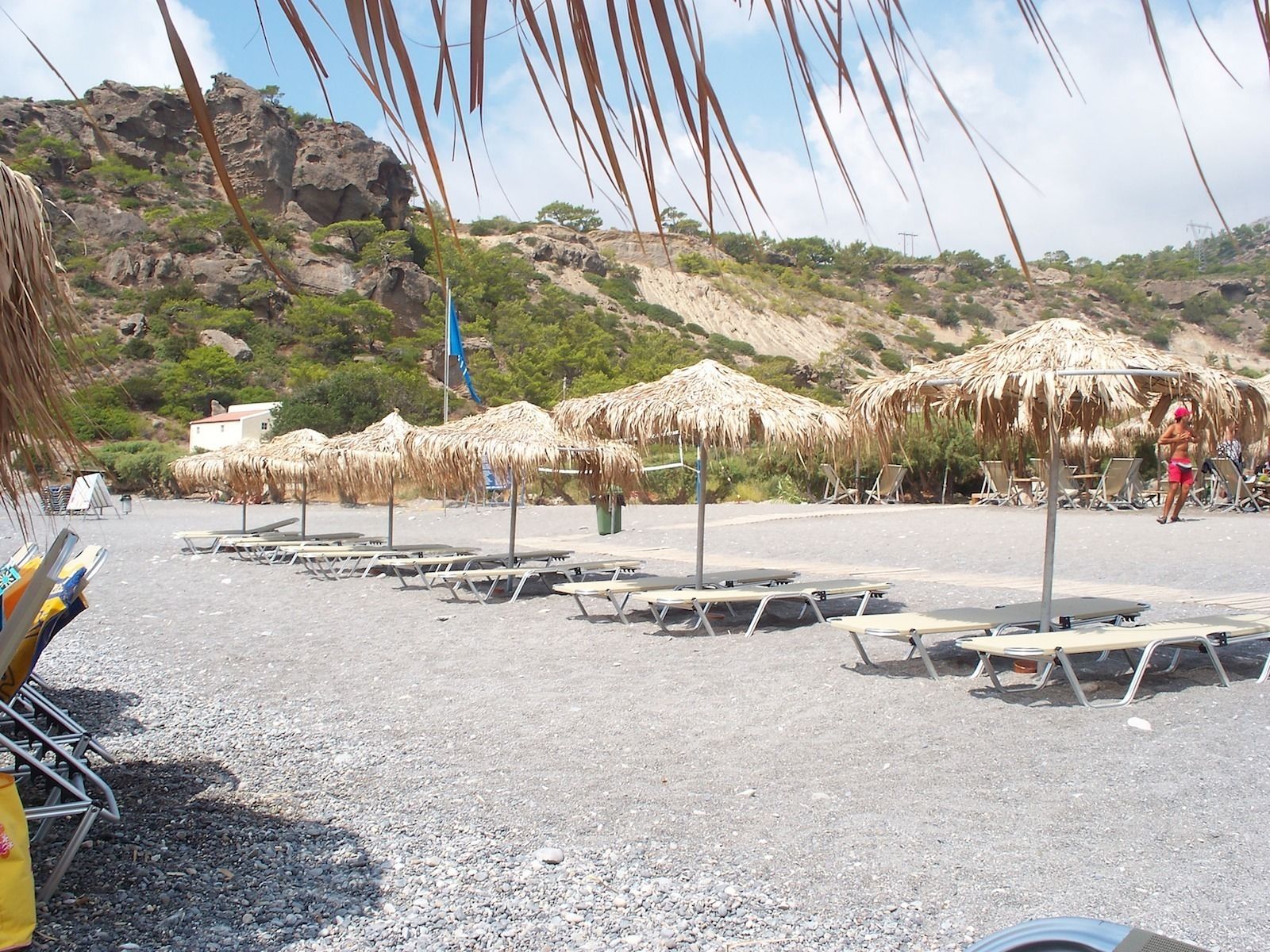 A beach with thatched umbrellas and sun loungers.