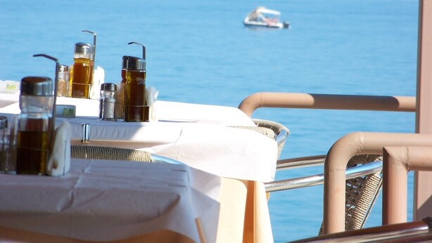 A table with various bottles and a sign labeled "Mythos" on a balcony overlooking the sea. - Agia Fotia (Ierapetra)