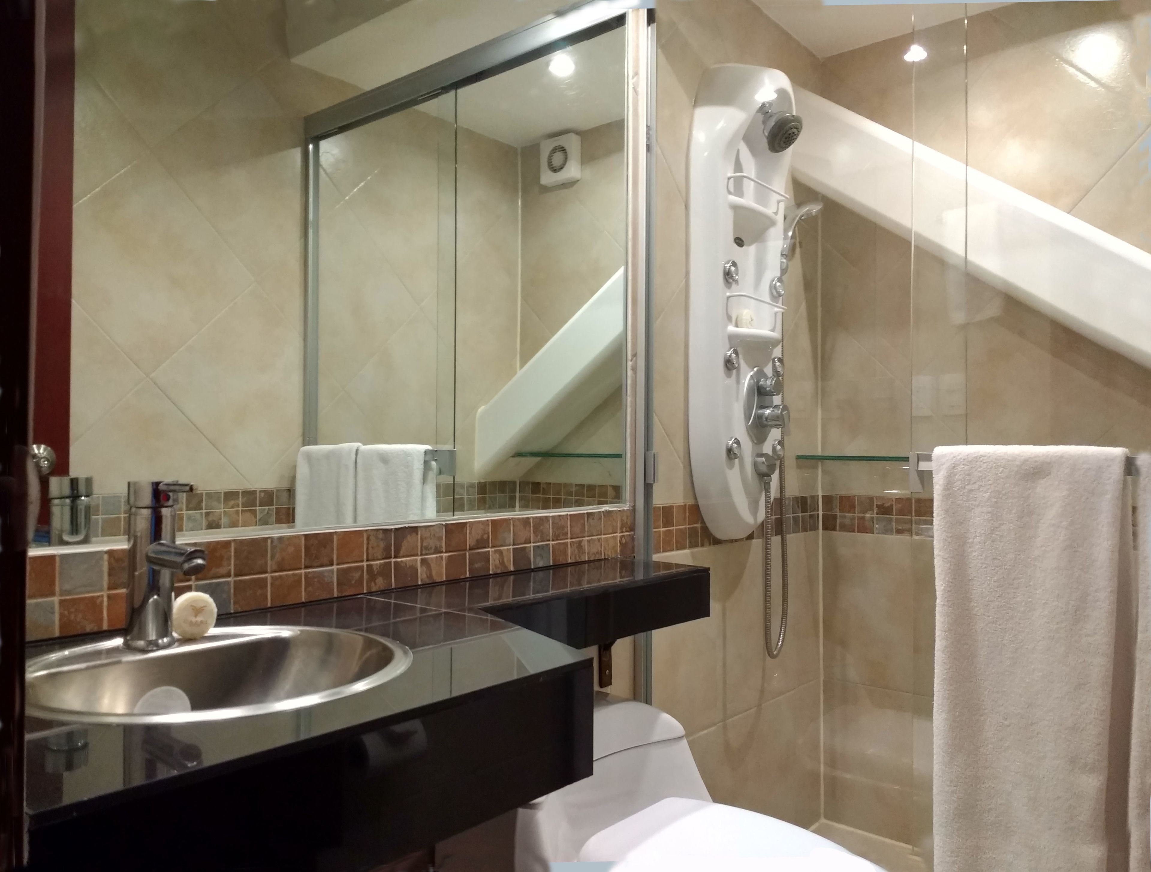 Een moderne badkamer met een douchecabine van glas, een wastafel met spiegel en een handdoekrek.