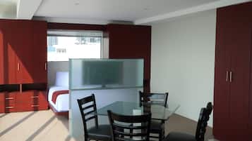 Cocina compacta con mesa de vidrio, dos sillas y un refrigerador.