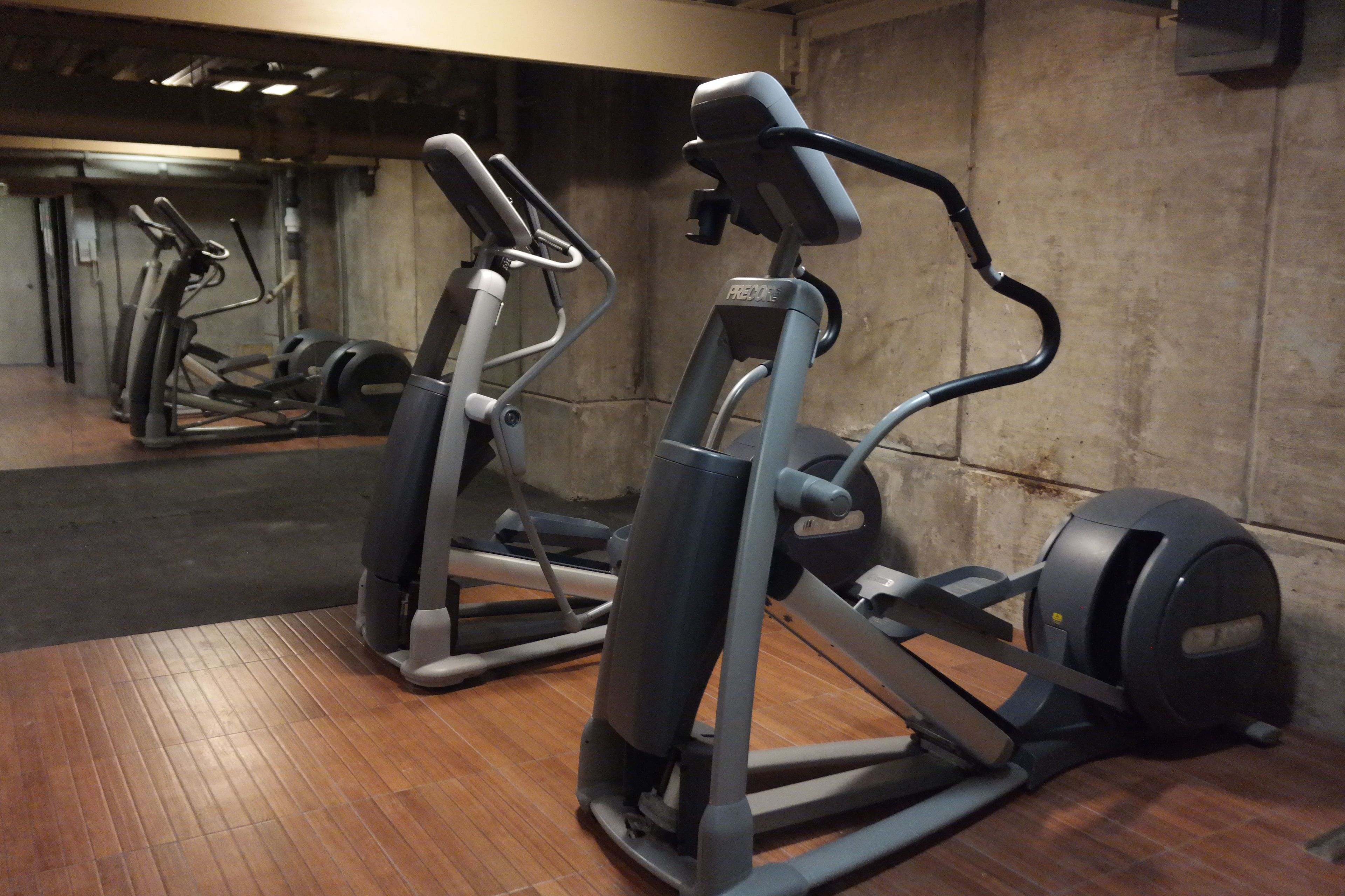 Un gimnasio con equipo de ejercicio, incluyendo máquinas elípticas y pesas.