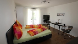 A bedroom with a bed, a desk, a chair, a television, and a window with curtains. - Apartment Wesseling Zentrum (Wesseling)