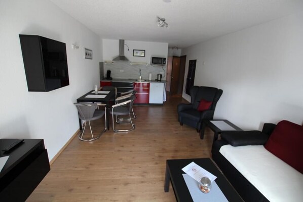 A modern living room with a sofa, a coffee table, and a TV mounted on the wall.