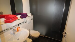 A bathroom with a sink, mirror, and toilet. There are folded towels in red and purple. - Apartment Wesseling Zentrum (Wesseling)