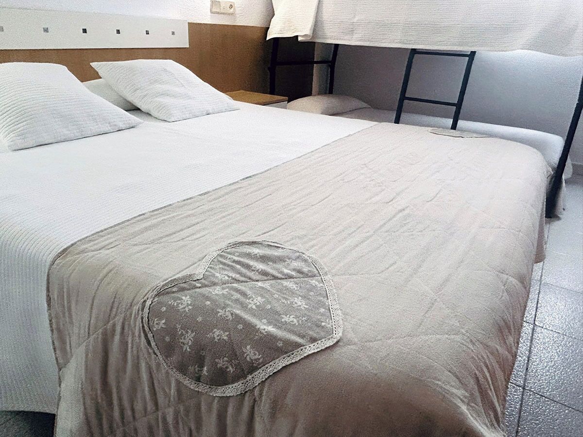 A hotel room with two beds, a headboard, and a bedside table.