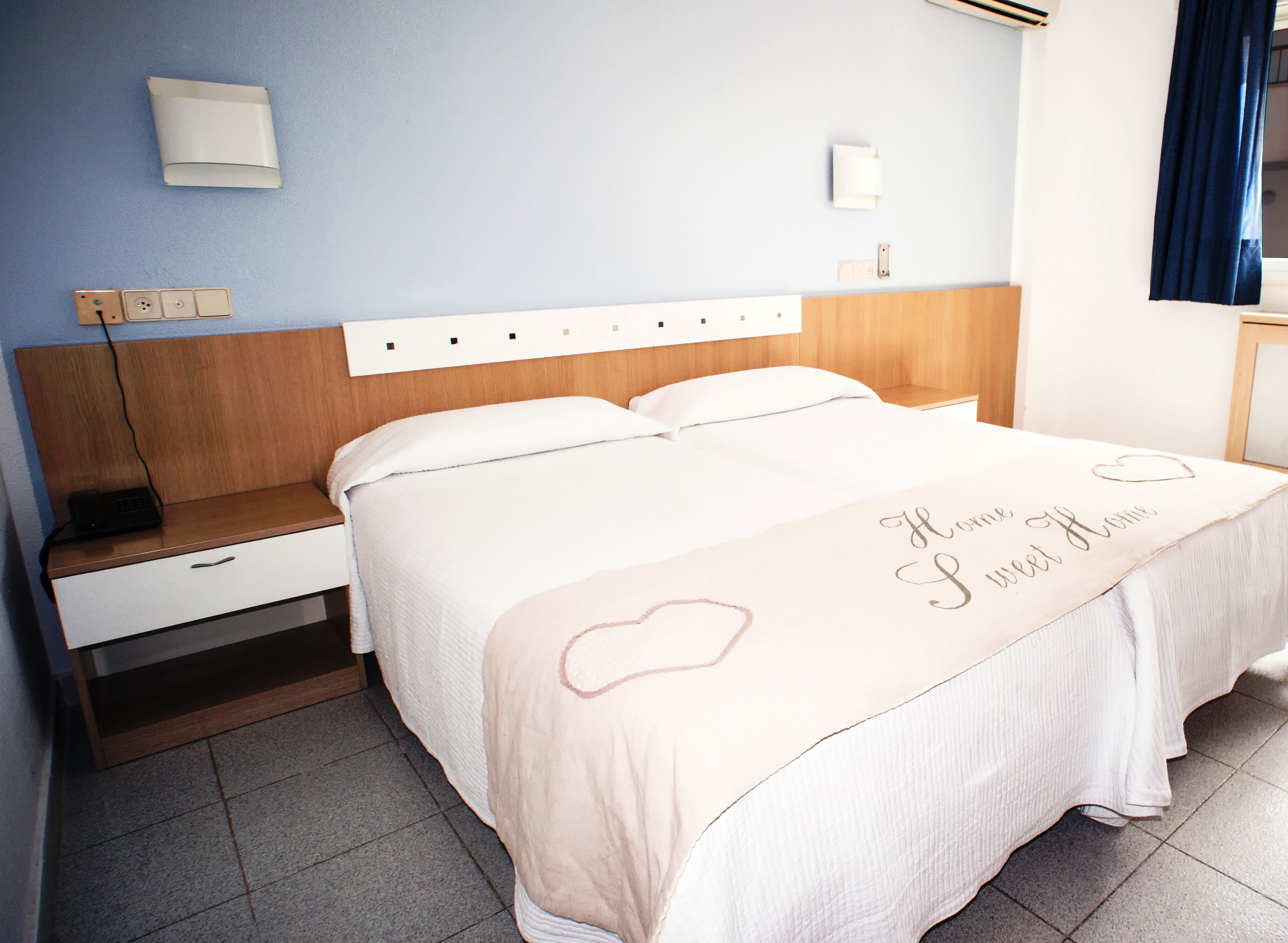 A hotel room with a bed, bedside table, and a nightstand.