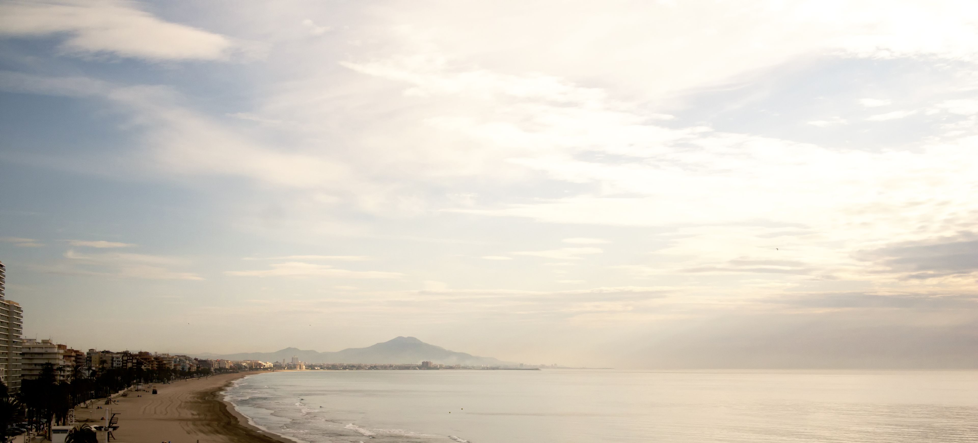 Una playa con vista al océano y una montaña al fondo.