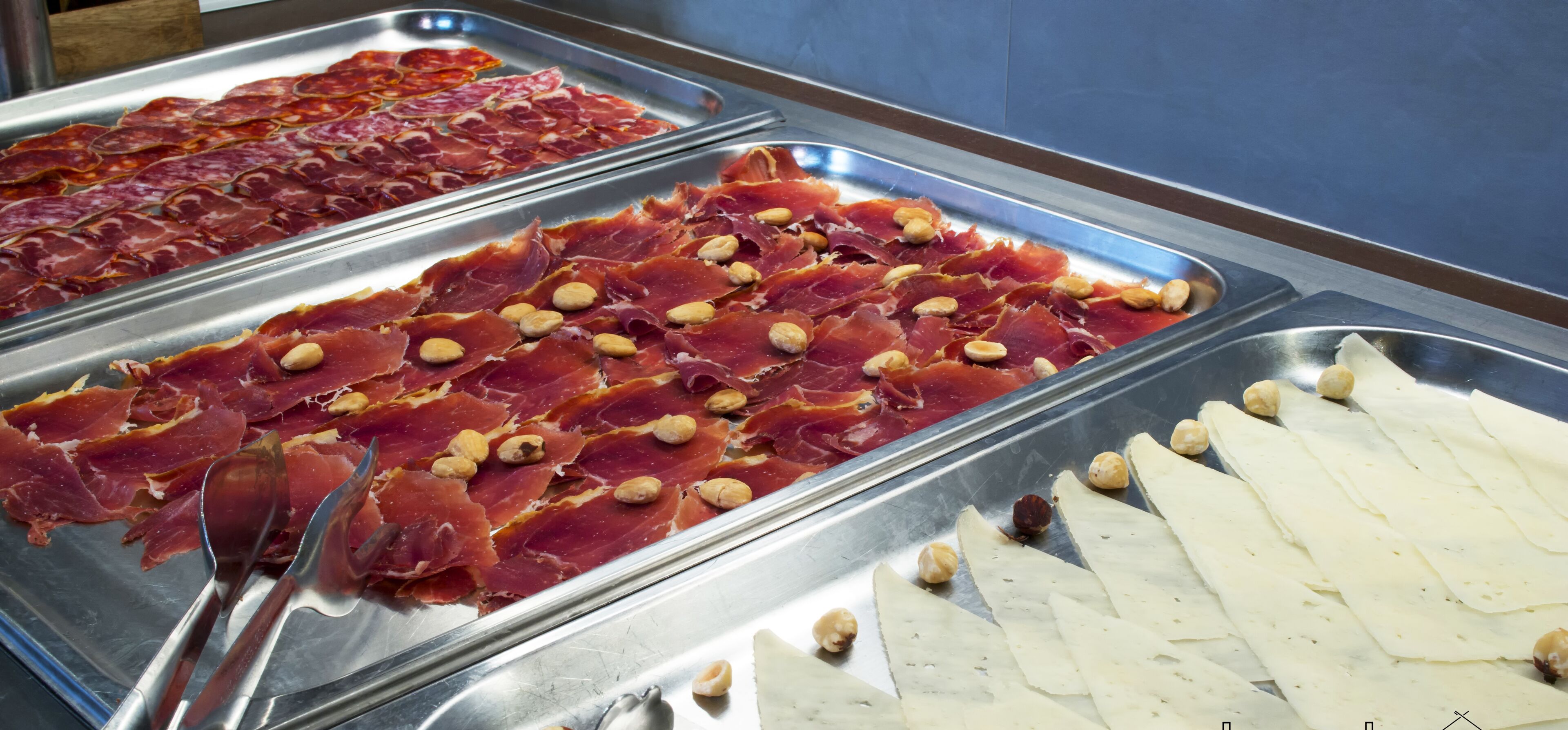 A buffet with various food items including sliced meats and nuts.